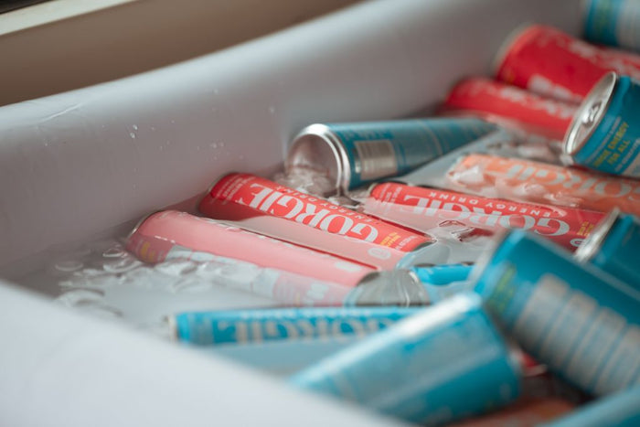 Refreshing cans of pink and blue Gorgie energy drinks chilling in an ice bath during a rooftop fitness event in San Diego. - Sip & Social Club San Diego event