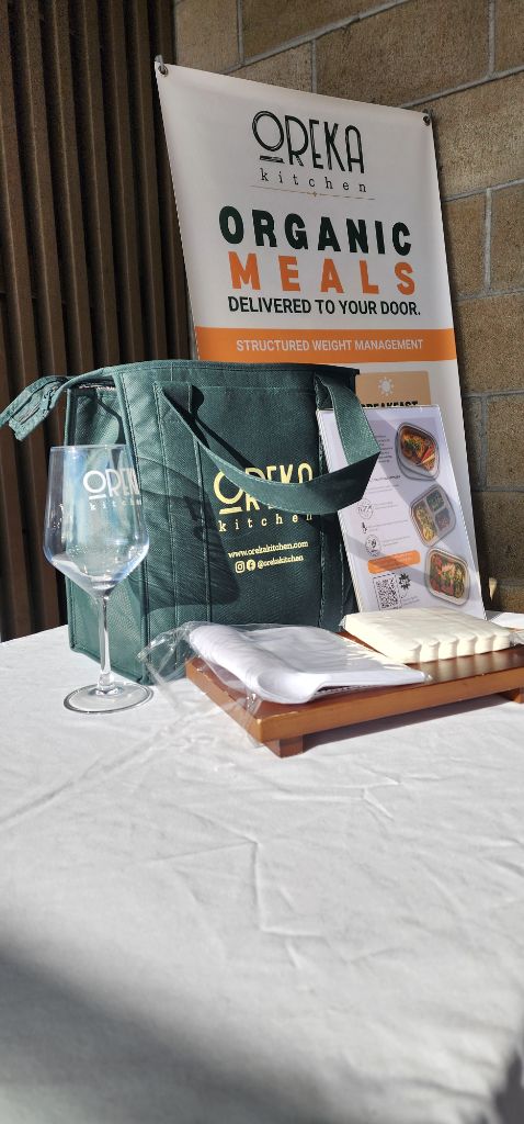 Oreka Kitchen organic meal prep delivery bag and presentation display at a wellness event in San Diego. - Sip & Social Club San Diego event