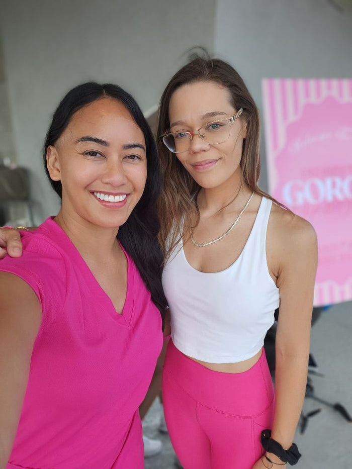 Two women smiling together in matching pink and white athletic outfits during a Sip and Social rooftop wellness event in San Diego. - Sip & Social Club San Diego event