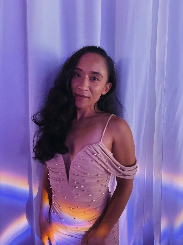 Genel Ronquillo, culture and community strategist at Sip and Social Club, in a blush dress against a softly lit curtain