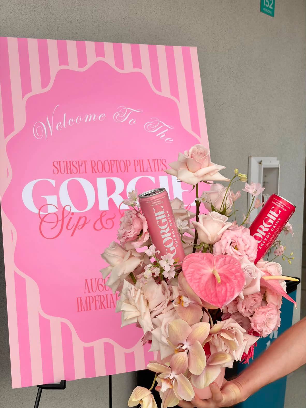 A pink welcome sign and floral arrangement at a Gorgie Energy Drink pop-up