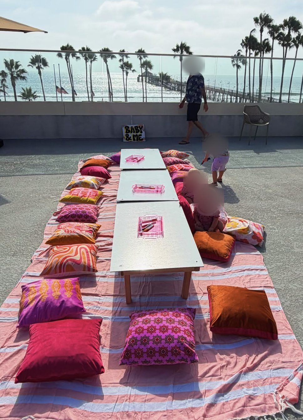 A low kids table with colorful floor pillows set up on the rooftop for a Baby and Me event
