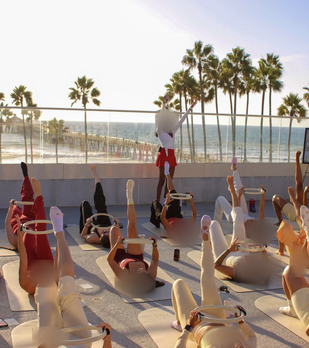 A sunset pilates class with rings on the rooftop, the pier behind them